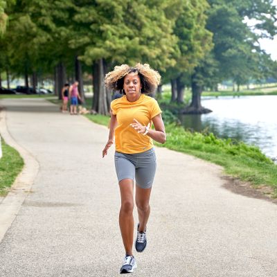 a woman running down a path next to a lake